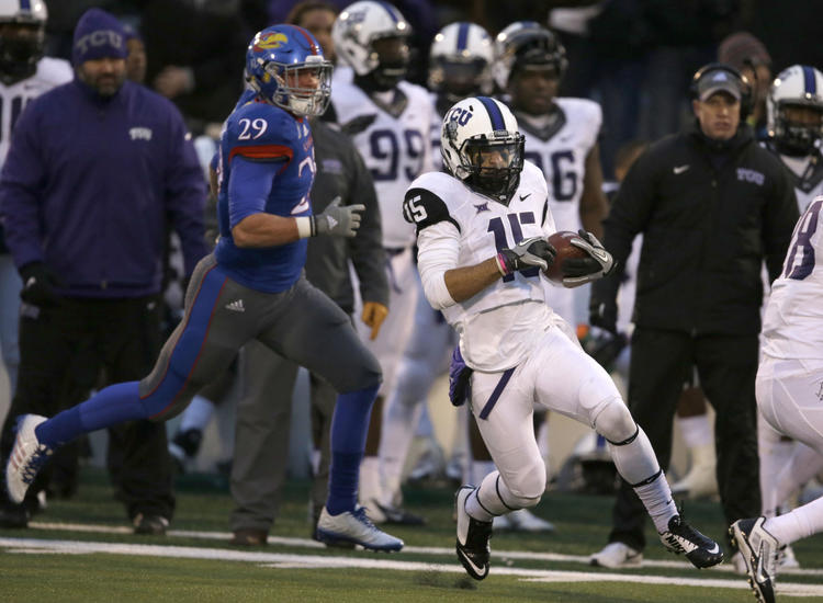 TCU punt returner Cameron Echols-Luper (15) cuts behind blockers and ahead of Kansas special teams player Joe Dineen Jr. (29) on his way for a touchdown during the second half of an NCAA college football game in Lawrence, Kan., Saturday, Nov. 15, 2014. TCU defeated Kansas 34-30.