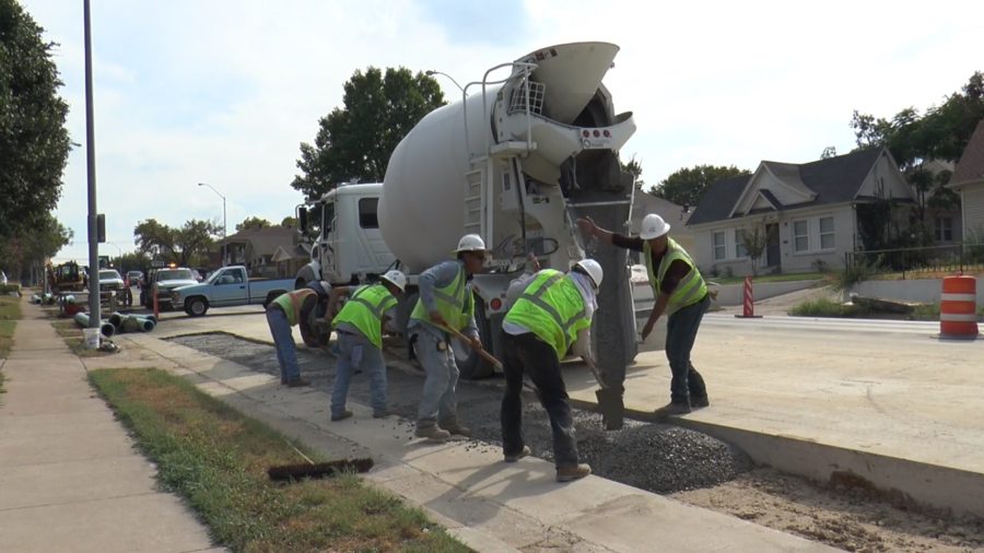 Construction workers pour concrete on University Drive by TCU.
