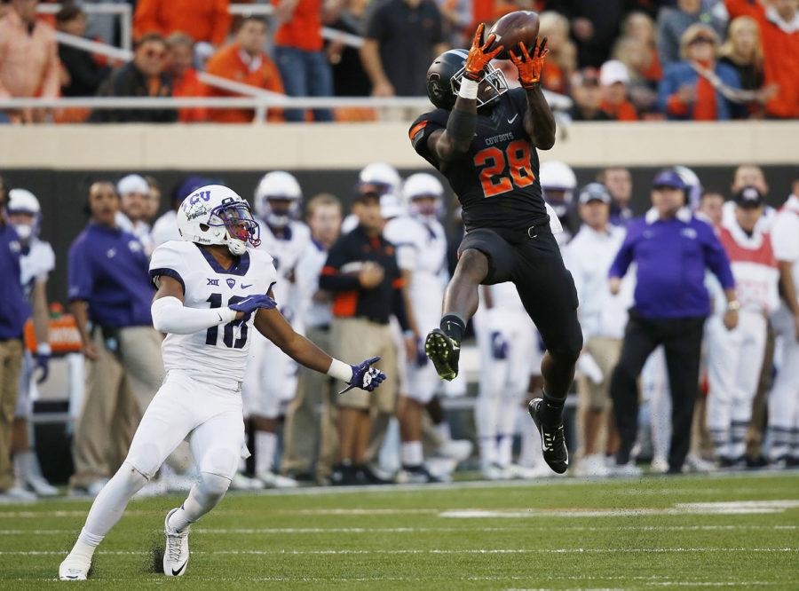 Oklahoma State wide receiver James Washington (28) leaps up for a pass in front of TCU safety Nick Orr (18) in the third quarter of an NCAA college football game in Stillwater, Okla., Saturday, Nov. 7, 2015. Washington took the pass into the end zone for a touchdown and Oklahoma State won 49-29. (AP Photo/Sue Ogrocki)