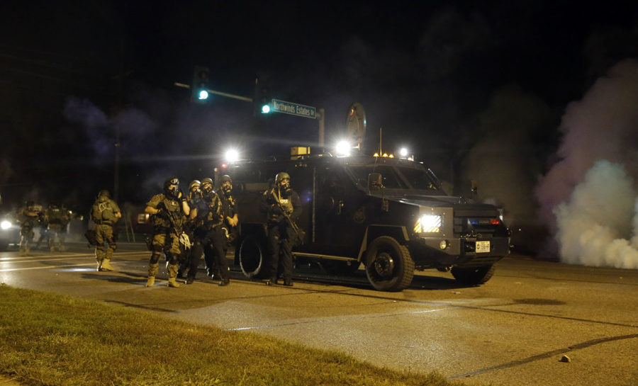 Police is riot gear work to disperse a crowd of protesters Monday, Aug. 18, 2014, in Ferguson, Mo. The protests were sparked after Michael Brown, an unarmed black man was shot and killed by Darren Wilson, a white Ferguson police officer on Aug. 9, 2014. (AP Photo/Jeff Roberson)