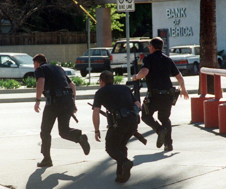Unidentified Los Angeles police officers move in at the Bank of America in the North Hollywood section of Los Angeles Friday, Feb. 28, 1997. Wearing commando garb, several heavily armed, masked robbers bungled a bank heist, then fired hundreds of shots in a gun battle getaway try that left two dead, at least 11 hurt and a broad trail of damage. (AP Photo/Mike Meadows)