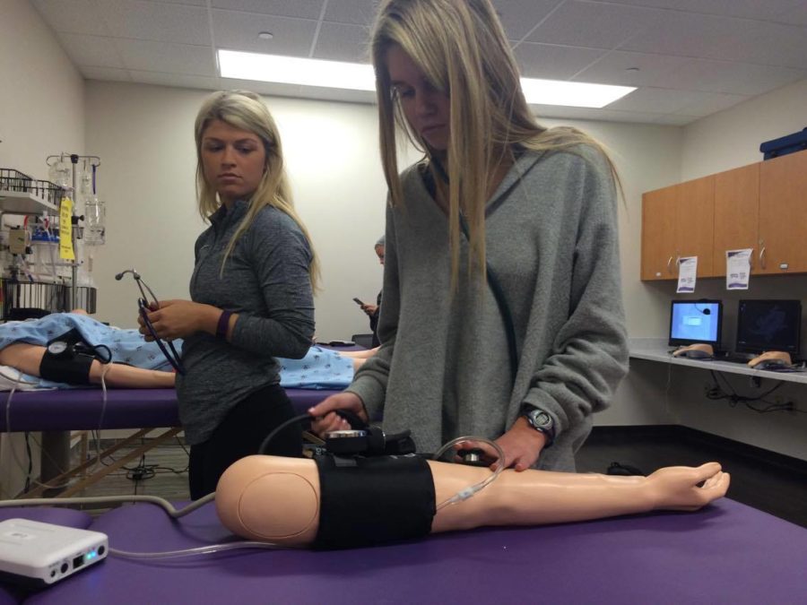 Nursing majors Lindsay Brady and Kendall Frenkel practice taking vital signs on a manakin. 