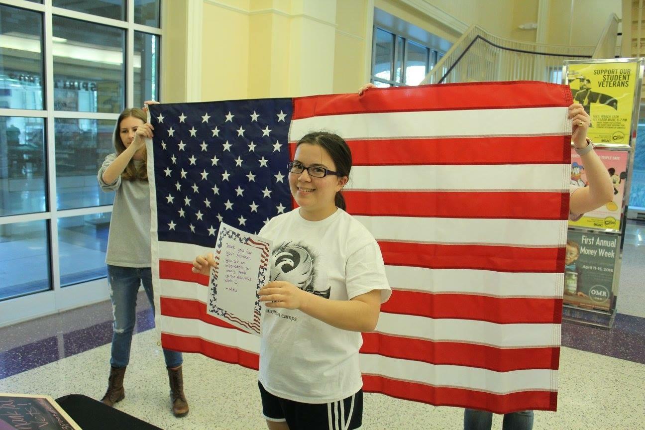 Student poses in front of the American flag with her letter.