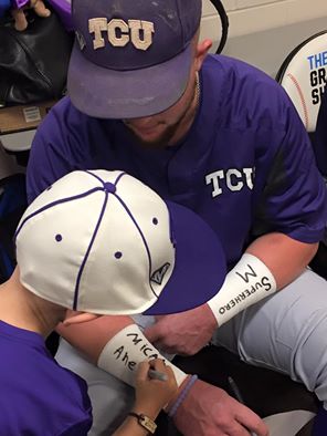 Micah Ahern signs his name on TCU catcher Evan Skoug's wristbands before the Frogs' game against Coastal Carolina in Omaha, Neb. on June 21. 