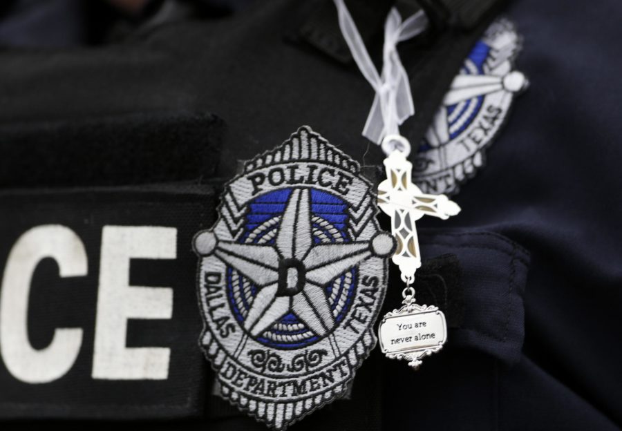 Dallas Police Sr. Corp. Kimberly Howard wears a cross given to her earlier in the day by a random well-wisher outside their headquarters in Dallas, Saturday, July 9, 2016. Security measures were heightened after a peaceful protest, over the recent shootings of black men by police, turned violent Thursday night when gunman Micah Johnson shot at officers, killing several and injuring others. (AP Photo/Gerald Herbert)