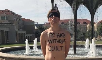 A TCU male student stands in front of Frog Fountain, silently protesting with 'To hate without guilt' on his chest. (Photo Credit: Kamry Henson)