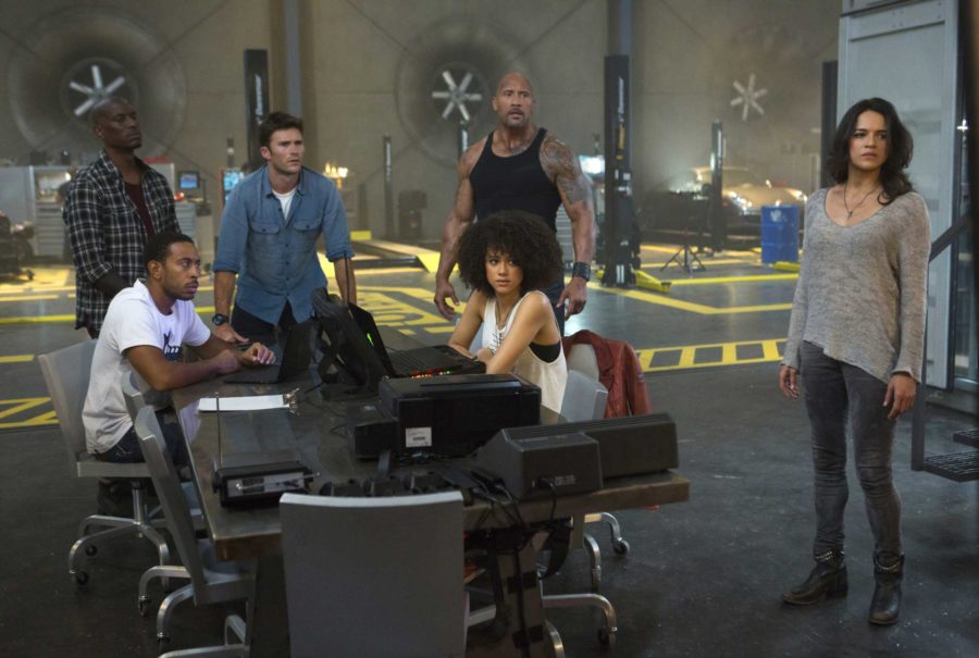 This image released by Universal Pictures shows, Chris Ludacris Bridges, seated left, and Nathalie Emmanuel, seated right, and Tyrese Gibson, standing from left, Scott Eastwood, Dwayne Johnson and Michelle Rodriguez in The Fate of the Furious. (Matt Kennedy/Universal Pictures via AP)