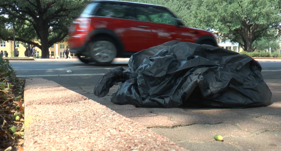 Cars drive by a discarded trash bag on University Drive.