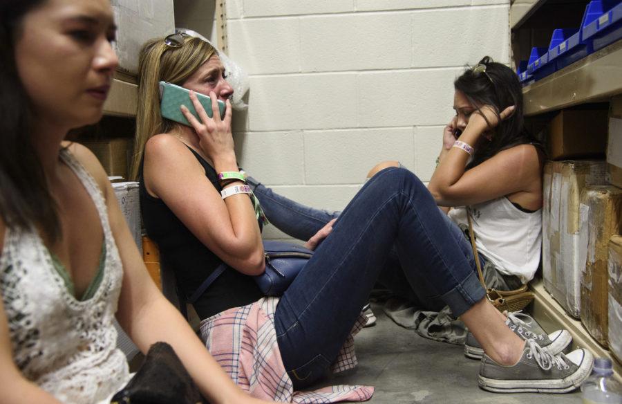 Women make phone calls while taking shelter inside the Sands Corporation plane hangar after a mass shooting in which dozens were killed at Route 91 Harvest Festival on Sunday, Oct. 1, 2017, in Las Vegas. (Al Powers/Invision/AP)