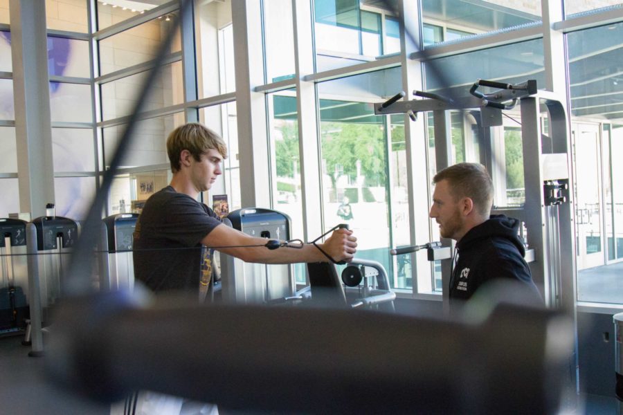 Personal trainer, Colton Purcell, talks through the motions of the exercise with his trainee at the TCU Recreation Center on Wednesday, Oct. 11, 2017. Photo by Carolina Olivares.