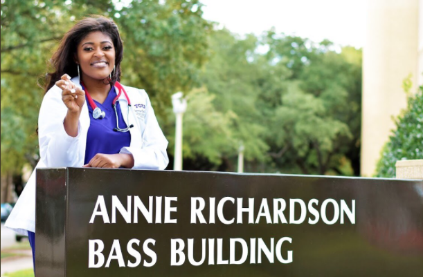 Nursing senior Indigo Dillard stands behind a sign for the Annie Richardson Bass building. (Photo courtesy of D. Oliver Photography).
