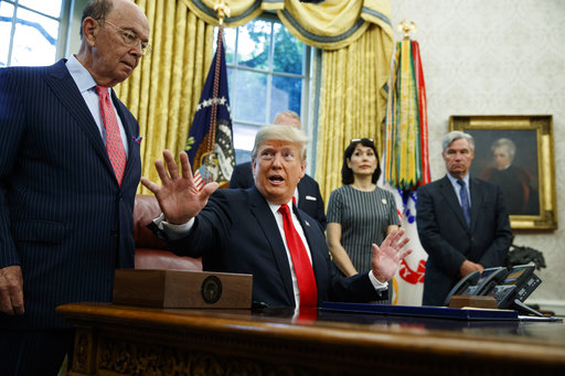 President Donald Trump talks with reporters during a signing ceremony for the Save Our Seas Act of 2018 in the Oval Office of the White House, Thursday, Oct. 11, 2018, in Washington. At left is Commerce Secretary Wilbur Ross. (AP Photo/Evan Vucci)