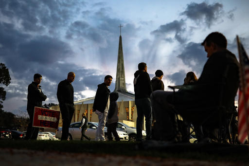 Adam Fohlen and his son Ari, center left, wait in line outside a polling place at the Nativity School as a poll watcher who refused to be identified sits nearby, Tuesday, Nov. 8, 2016, in Cincinnati. (AP Photo/John Minchillo)