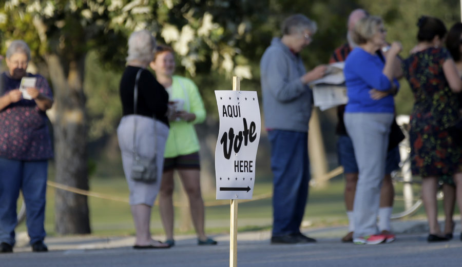 Voters stand in line to vote at an early voting polling site, Monday, Oct. 20, 2014, in San Antonio. Early voting began Monday across Texas. The U.S. Supreme Court this weekend gave Texas permission to enforce a contested voter ID law this election. (AP Photo/Eric Gay)