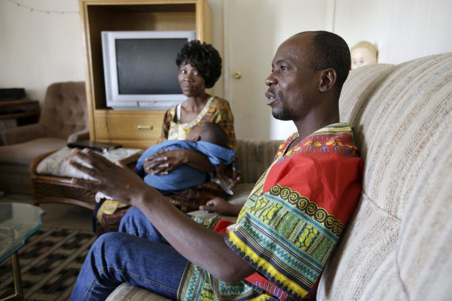 Bikole Mulanda of the Democratic Republic of Congo responds to a  question in an interview as his wife Fabiola Ongaobe Atonda holds their son Francois Rashidi Mulanda in her arms in the home they rent, Tuesday, Dec. 16, 2014, in Abilene, Texas. Mulanda, his wife and 6 children have been in America nearly two years. Texas has led the nation in refugee resettlements over the last four years and continues to attract others who move to the state on their own.  (AP Photo/Tony Gutierrez)