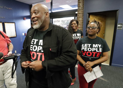 Former felon Desmond Meade and president of the Florida Rights Restoration Coalition, left, arrives with family members at the Supervisor of Elections office Tuesday, Jan. 8, 2019, in Orlando, Fla., to register to vote. Former felons in Florida began registering for elections on Tuesday, when an amendment that restores their voting rights went into effect. (AP Photo/John Raoux)