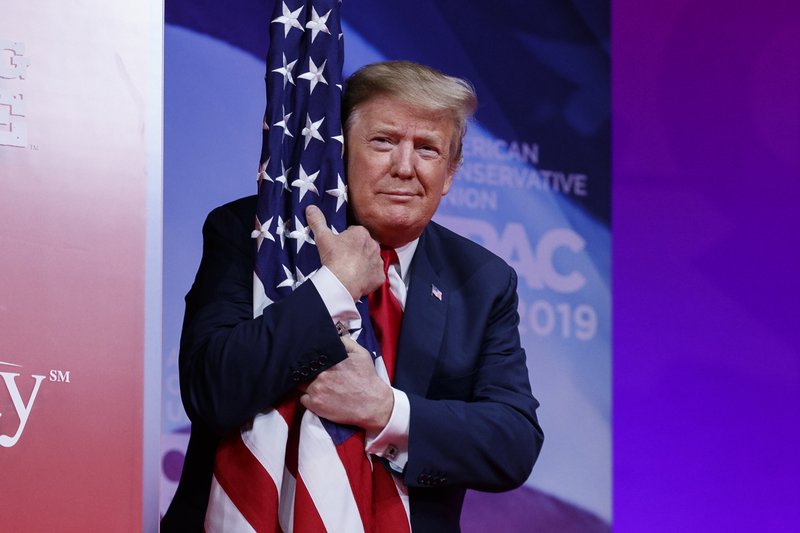 President Trump hugs the American flag during the Conservative Political Action Conference. (Photo provided by The Associated Press.)
