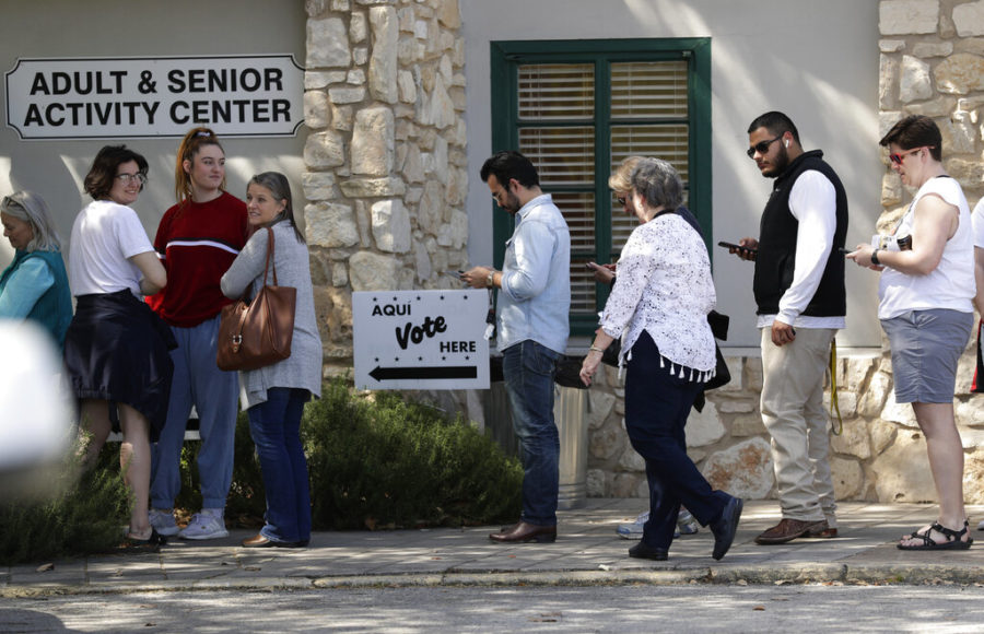 In this Friday, Feb. 28, 2020 photo, voters wait in line at an early polling site in San Antonio. California and Texas are the most populous states in the nation and the biggest delegate prizes for the candidates, yet they also present a stark contrast in voting laws. (AP Photo/Eric Gay)