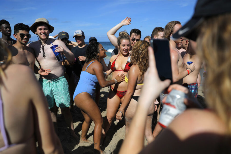 College age spring break students party on the beach, Tuesday, March 17, 2020, in Pompano Beach, Fla. As a response to the coronavirus pandemic, Florida Gov. Ron DeSantis ordered all bars be shut down for 30 days beginning at 5 p.m. and many Florida beaches are turning away spring break crowds urging them to engage in social distancing. (AP Photo/Julio Cortez)