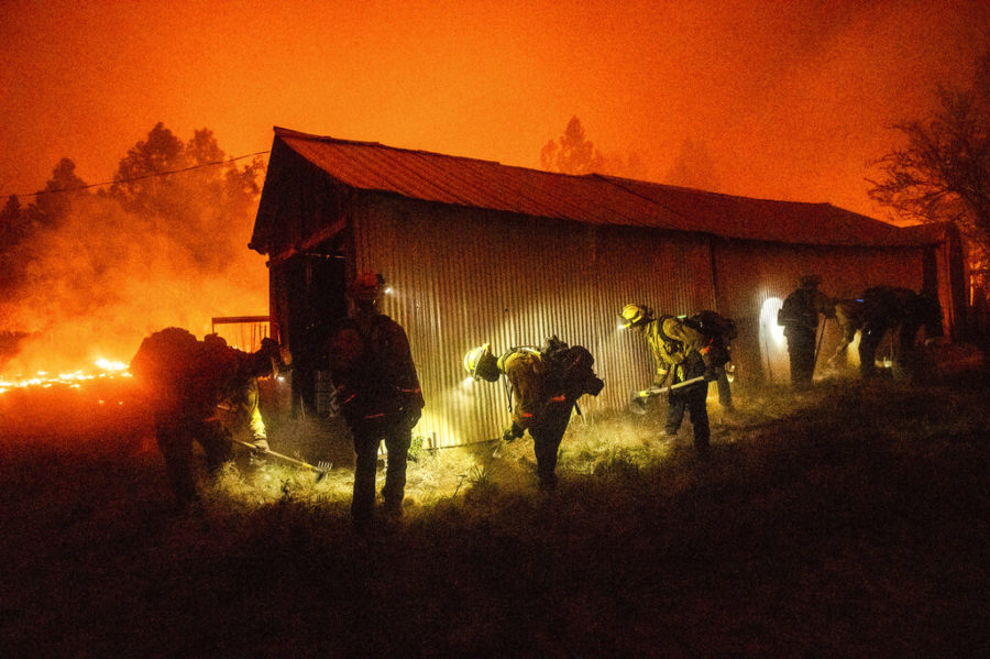 FILE - In this Sept. 9, 2020 file photo, a hand crew clears vegetation from around a barn as the Bear Fire burns through the Berry Creek area of Butte County, Calif. Two years before a deadly fire leveled Berry Creek, the community was selected to receive an $836,000 state grant for pruning vegetation and clearing fuel from potential fire spots. But the forest management project was never completed because of red tape, said local officials, who now wonder if having cleared potential fuel could have changed the fortunes of Berry Creek, the San Francisco Chronicle reported Thursday, Sept. 17, 2020 (AP Photo/Noah Berger, File)