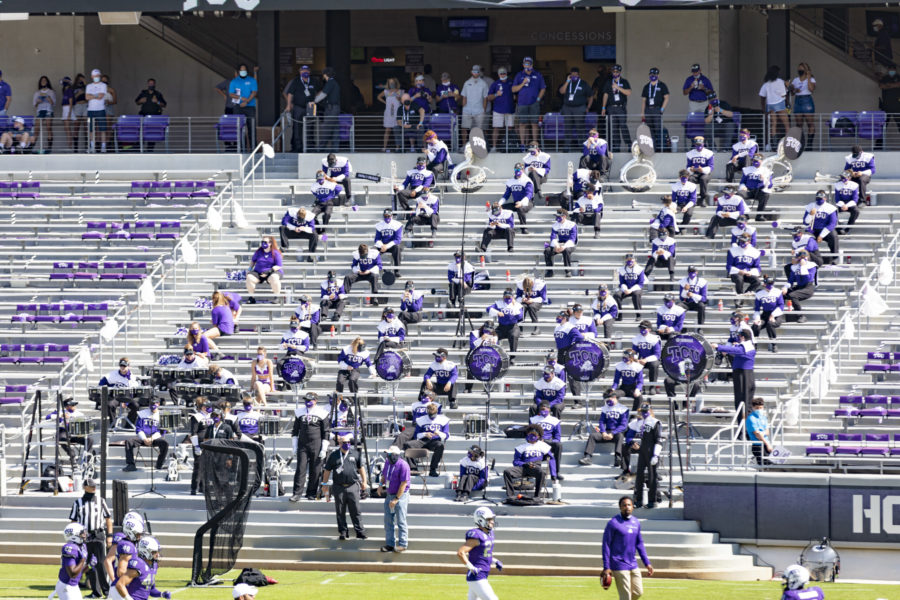 TCU Band members sit socially distant in the stands during a football game.
