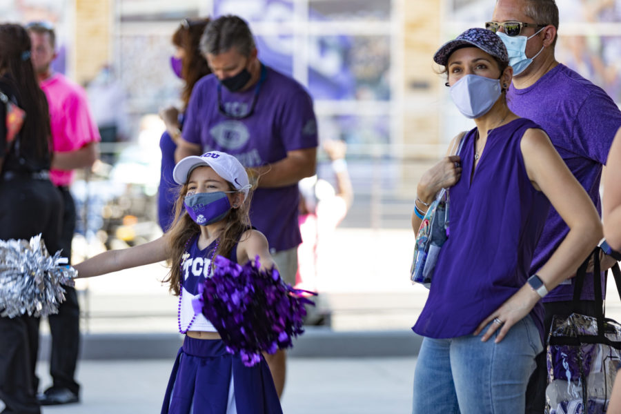 A young girl cheers on the TCU Football team along with her family.