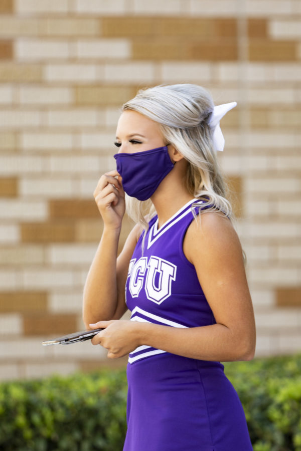 TCU Cheerleader adjusts mask at TCU Football game against Iowa State.