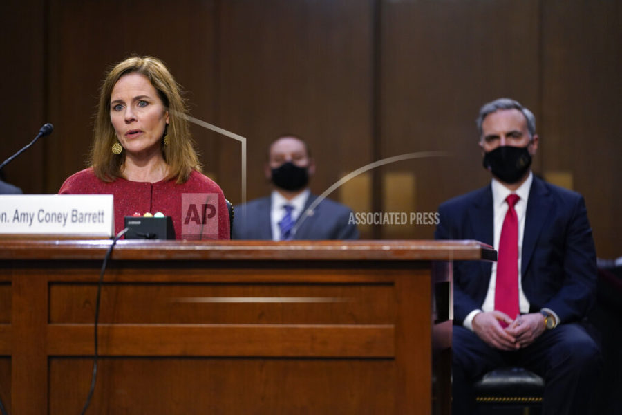 Supreme Court nominee Amy Coney Barrett speaks during a confirmation hearing before the Senate Judiciary Committee, Tuesday, Oct. 13, 2020, on Capitol Hill in Washington. Her family looks on at left. White House counsel Pat Cipollone sits right. (AP Photo/Patrick Semansky, Pool)