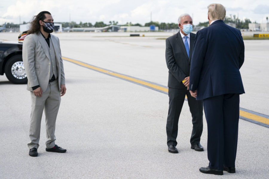 President Donald Trump is greeted by UFC fighter Jorge Masvidal, left, and Miami-Dade County Mayor Carlos Gimenez after arriving at Miami International Airport, Thursday, Oct. 15, 2020, in Miami. (AP Photo/Evan Vucci)