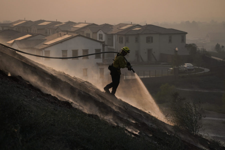 Firefighter Tylor Gilbert puts out hotspots while battling the Silverado Fire, Monday, Oct. 26, 2020, in Irvine, Calif. A fast-moving wildfire forced evacuation orders for 60,000 people in Southern California on Monday as powerful winds across the state prompted power to be cut to hundreds of thousands to prevent utility equipment from sparking new blazes. (AP Photo/Jae C. Hong)