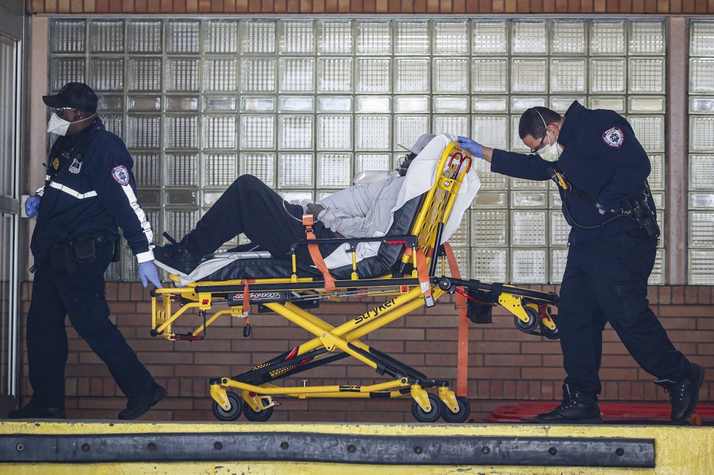 Paramedics wheel a patient wearing a breathing apparatus into the emergency room at Wyckoff Heights Medical Center, in New York. The new coronavirus causes mild or moderate symptoms for most people, but for some, especially older adults and people with existing health problems, it can cause more severe illness or death. (AP Photo/John Minchillo)