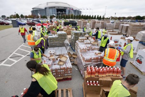 Volunteers build bags of dry goods in a parking lot outside of AT&T Stadium during a Tarrant Area Food Bank mobile pantry distribution event in Arlington, Texas, Friday, Nov. 20, 2020. Cars lined the surrounding streets around the home of the Dallas Cowboys and the nearby Texas Rangers Globe Life Field as Thanksgiving holiday food items were distributed to over 5,000 families. (AP Photo/Tony Gutierrez)