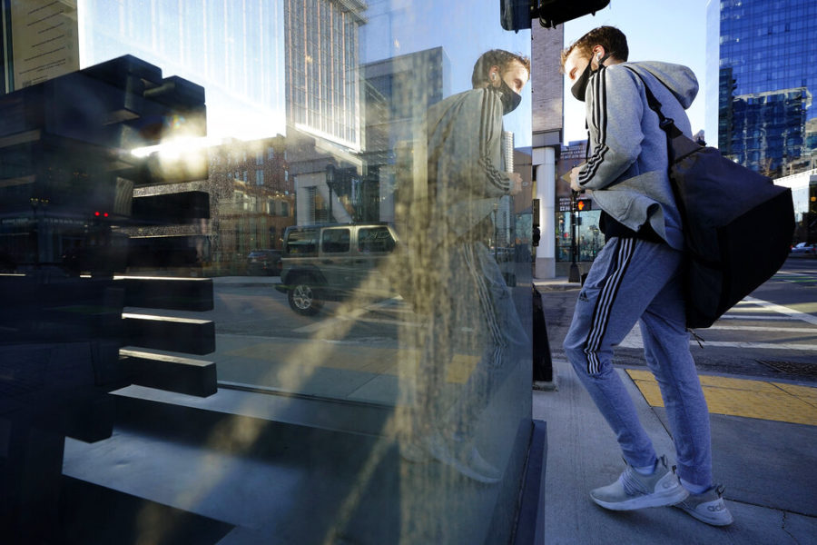 A passer-by walks near an entrance to a business in the Seaport District of Boston, Wednesday, Feb. 24, 2021. (AP Photo/Steven Senne)