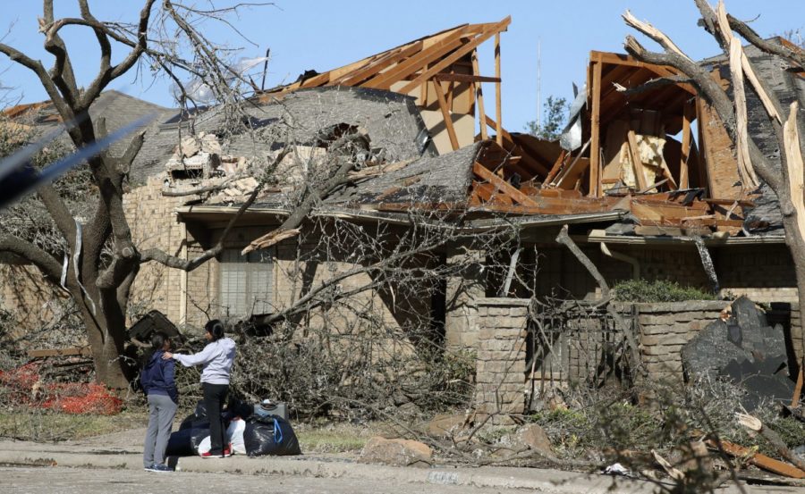 Women stand outside a house damaged by a tornado in the Preston Hollow section of Dallas, Monday, Oct. 21, 2019. (AP Photo/LM Otero)