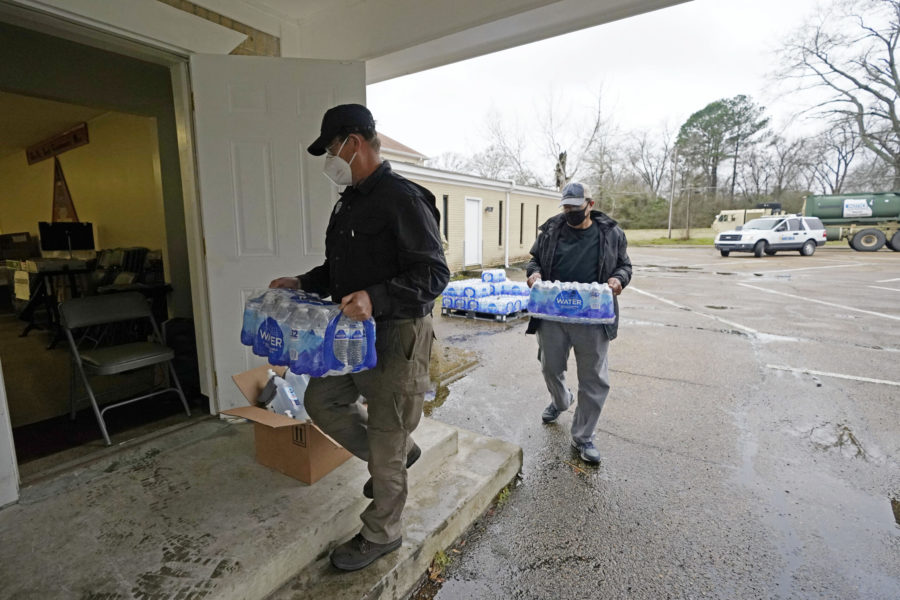 David Battaly with the Mississippi Emergency Management Agency, left, and Ralph Woullard, a member of the New Mt. Zion Missionary Baptist Church, carry cases of bottled water inside the church, Monday, March 1, 2021, at a Jackson, Miss., water distribution site on the churchs parking lot. The bottled water as well as non-potable water was provided for area residents and was being distributed at seven sites in Mississippis capital city — more than 10 days after winter storms wreaked havoc on the citys water system because the system is still struggling to maintain consistent water pressure, authorities said. (AP Photo/Rogelio V. Solis)
