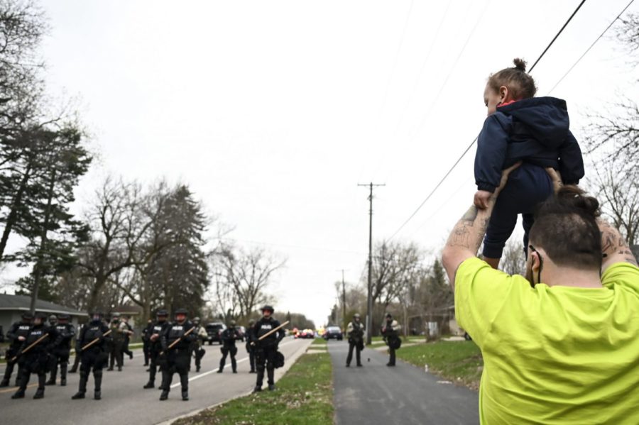Damik Wright, brother of Daunte Wright, who the family said was shot and killed earlier Sunday by police, holds Dauntes son Daunte Jr., over his head to look at police officers assembling with riot gear at 63rd Avenue North and Lee Avenue North, Sunday, April 11, 2021, in Brooklyn Center, Minn. (Aaron Lavinsky/Star Tribune via AP)
