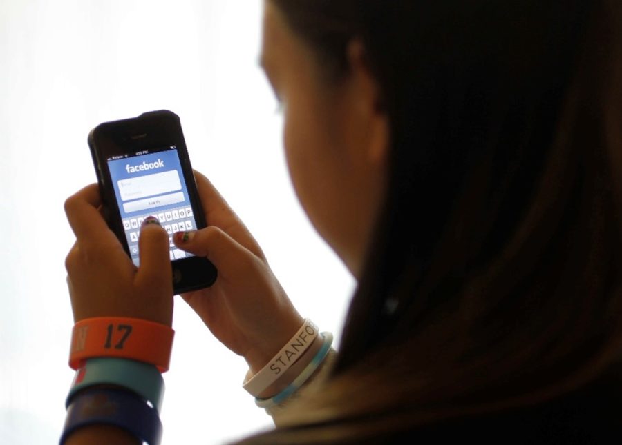 In this June 4, 2012, file photo, an unidentified 11-year-old girl logs into Facebook on her iPhone at her home in Palo Alto, Calif. Facebook, in the aftermath of damning testimony that its platforms harm children, will be introducing several features including prompting teens to take a break using its photo-sharing app Instagram, and “nudging teens if they are repeatedly looking at the same content thats not conducive to their well-being. (AP Photo/Paul Sakuma, File)