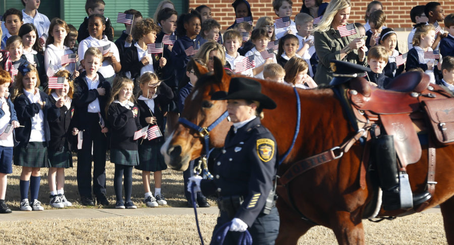 Children from the Prestonwood Christian Academy watch as a riderless horse is escorted to the funeral service for Little Elm Police Department Det. Jerry Walker at Prestonwood Baptist Church in Plano, Texas, Tuesday, Jan. 24, 2017. Fort Worth Mounted Patrol officer Cathy Fowler takes the reins.  (Tom Fox/The Dallas Morning News via AP, Pool)