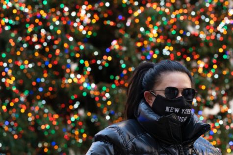 A woman walks by the Rockefeller Center Christmas Tree, Thursday, Dec. 3, 2020 in New York.  What’s normally a chaotic, crowded tourist hotspot during the holiday season is instead a mask-mandated, time-limited, socially distanced locale due to the coronavirus pandemic.  (AP Photo/Mark Lennihan)