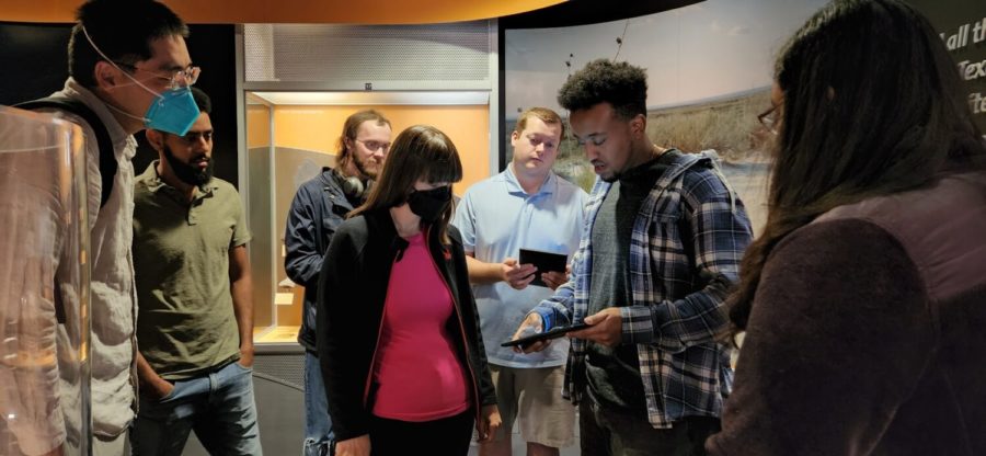 Amanuel Taddesse, second from right, shows off his team’s project to curator Rhiannon Mayne. Bingyang Wei’s computer science senior design team developed an app that can be downloaded onto tablets in the gallery. (Camilla Price/Copy Desk Chief)