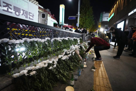 A woman places flowers to pay tribute for victims near the scene of a deadly accident in Seoul, South Korea, Sunday, Oct. 30, 2022, following Saturday nights Halloween festivities. A mass of mostly young people among tens of thousands who gathered to celebrate Halloween in Seoul became trapped and crushed as the crowd surged into a narrow alley, killing dozens of people and injuring dozens of others in South Korea’s worst disaster in years. (AP Photo/Ahn Young-joon)