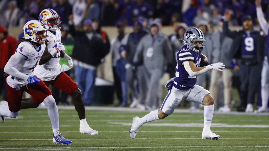 Kansas State running back Deuce Vaughn, right, rushes for a first down as Kansas safety Marvin Grant (4) and linebacker Craig Young (15) give chase. Nov. 26, 2022, in Manhattan, Kan. (AP Photo/Colin E. Braley)