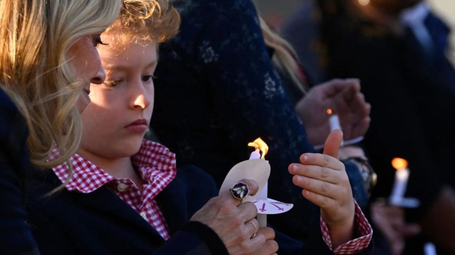 A+child+holds+a+candle+during+a+public+vigil+to+honor+victims+and+survivors+of+the+shooting+at+The+Covenant+School+in+Nashville.+%28John+Amins%2FAFP%29