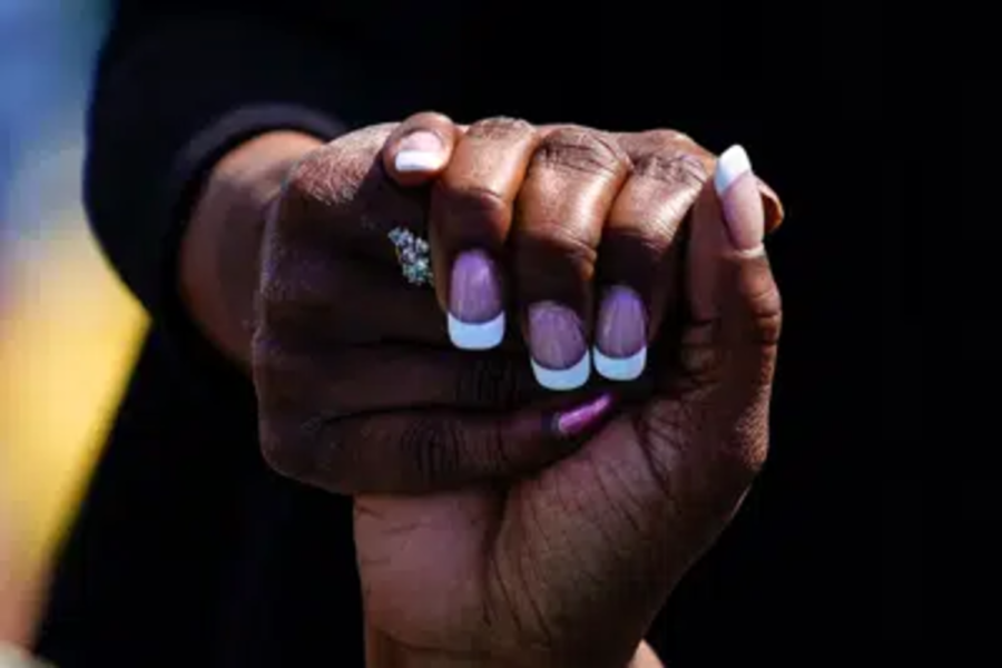 Two women show their nail art while holding hands. (Photo courtesy of AP News images)