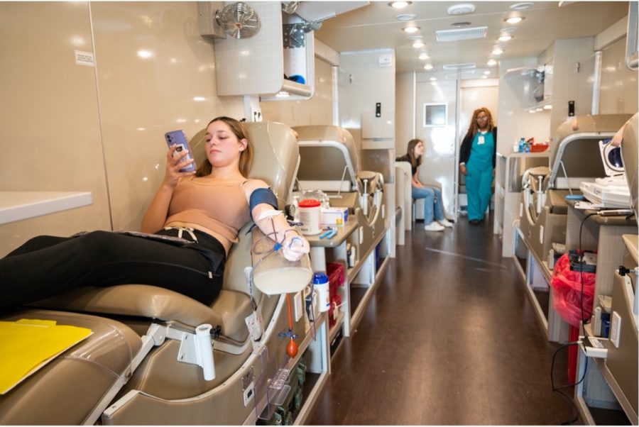 Hazel Remington, a TCU movement science major, donates to the TCU blood drive in the Carter BloodCare mobile unit Feb. 22, 2023. TCU student Abbie Orndorff, left, and Carter phlebotomist Destiny Milam, right, discuss the donating process. (Photo by Sally Verrando)