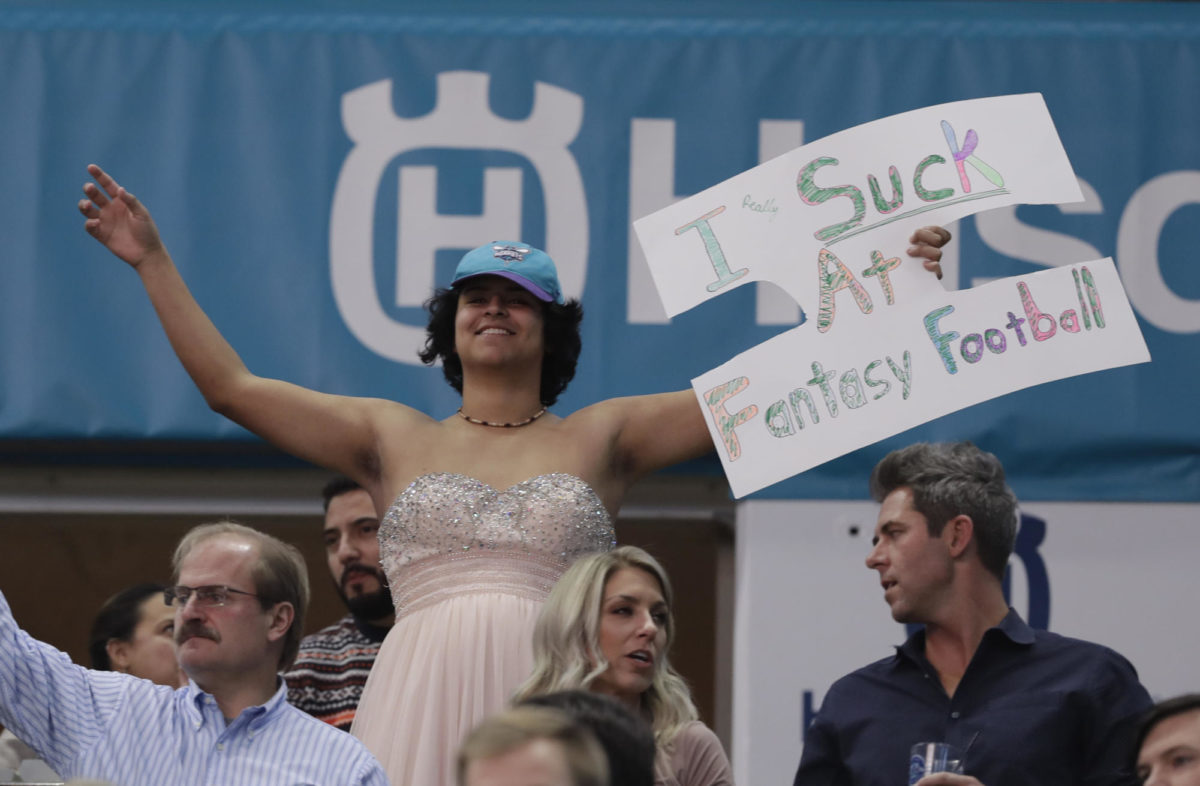 A man wearing a dress holds a sign after apparently losing at Fantasy Football. (AP Photo/Chuck Burton)