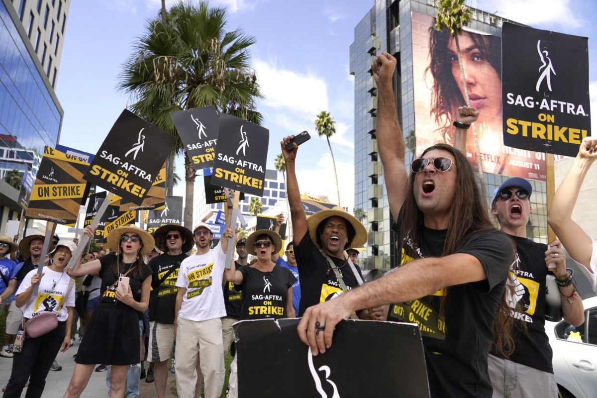 SAG-AFTRA member and others carry signs on the picket line outside Netflix on Wednesday, Sept. 27, 2023, in Los Angeles. (AP Photo/Chris Pizzello)