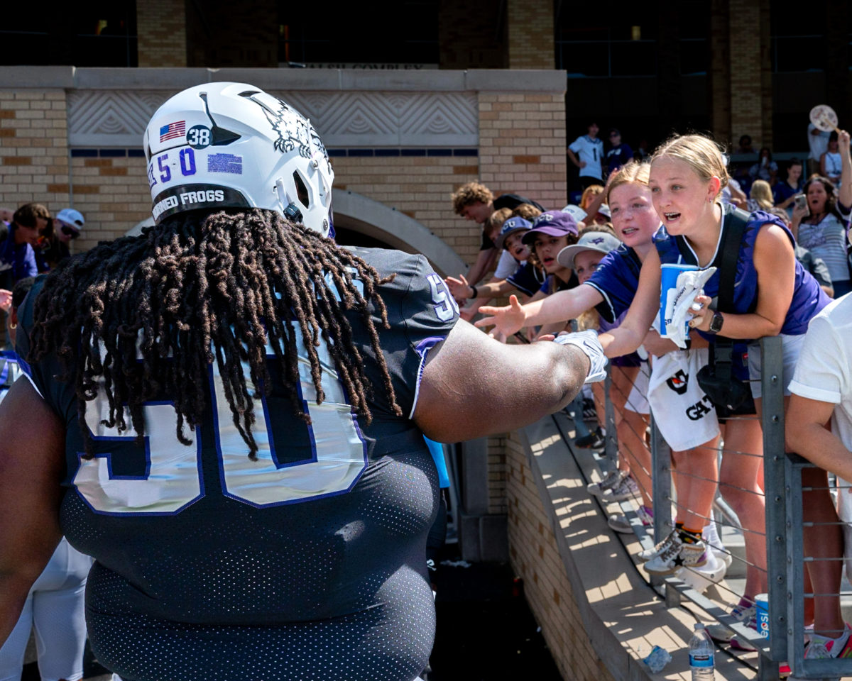 Texas Christian University offensive lineman Brione Ramsey-Brooks greets a young fan at Amon G. Carter Stadium in Fort Worth, Texas, Sept. 23, 2023. The TCU Horned Frogs beat the SMU Mustangs 34-17. (TCU 360/Shane Manson)
