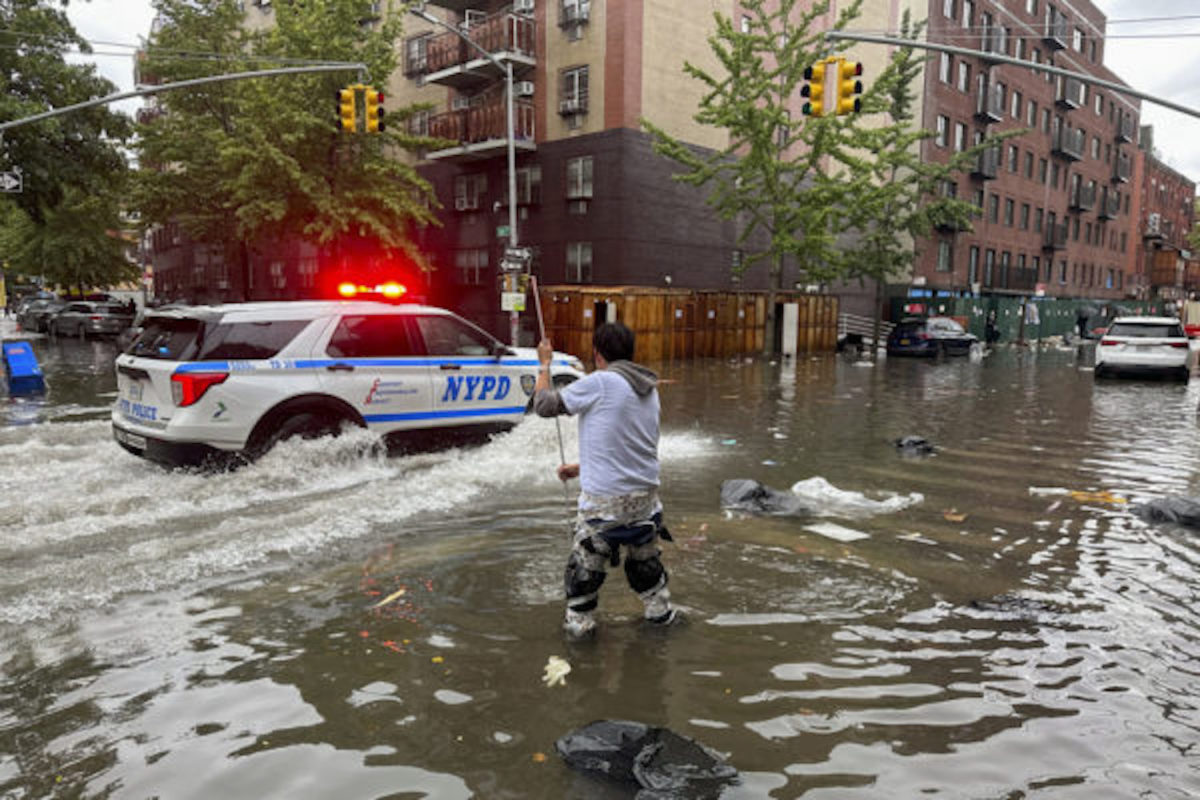 A man works to clear a drain in flood waters in the Brooklyn borough of New York. (AP Photo/Jake Offenhartz)
