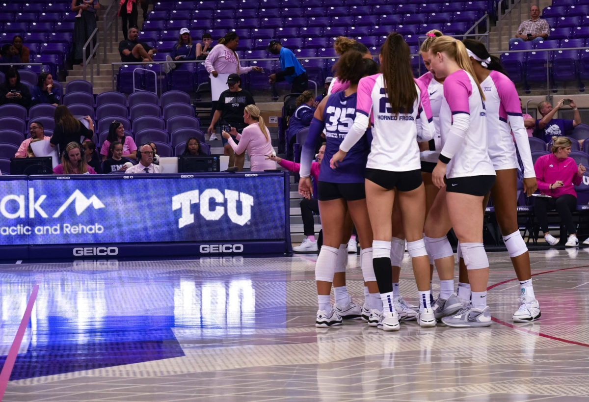 TCU Volleyball in a huddle before match one of their series with the Cincinnati Bearcats in their Pink Out uniforms for Breast Cancer Awareness. (Sarah Smith/Staff Writer)